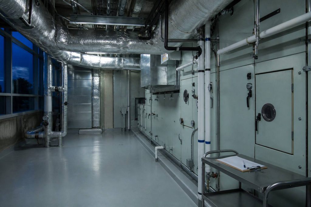 Hospital mechanical space with a large air-handling unit and insulated ducts at dusk